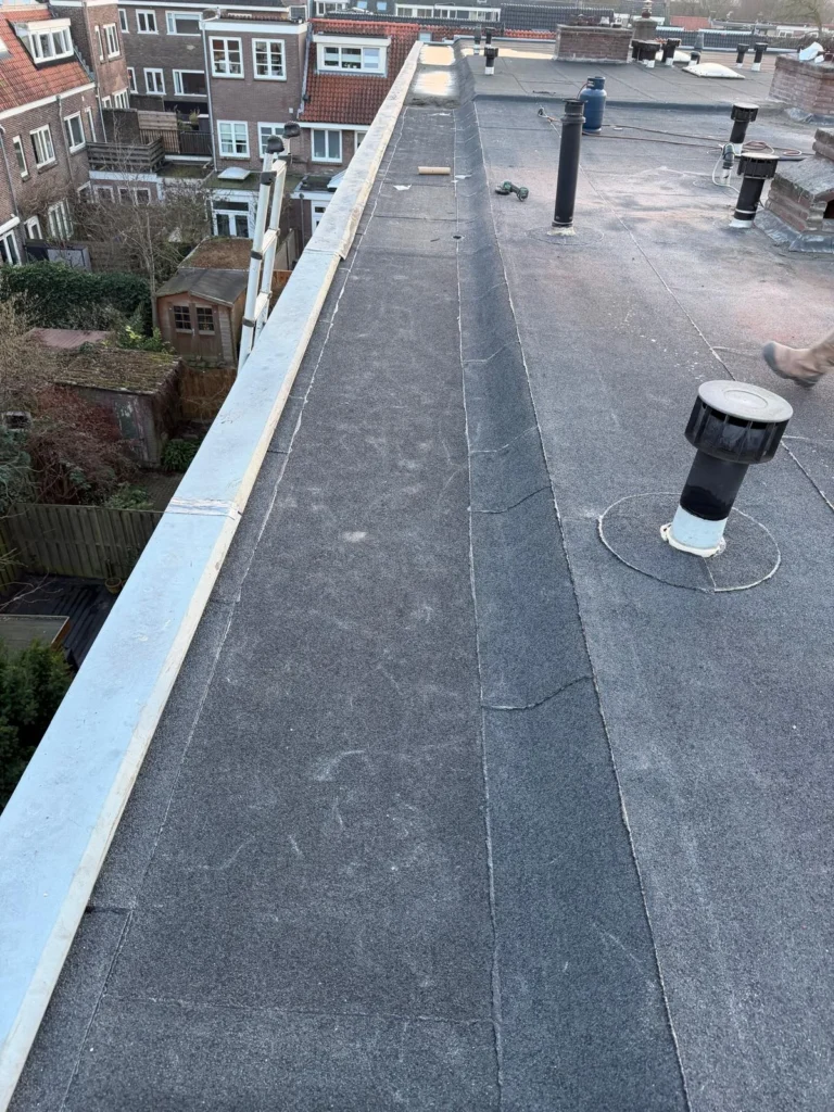 Bitumen plat dak met dakrandafwerking en ontluchter op rijtjeswoningen in Ede