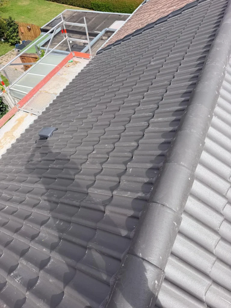 Nieuw grijs pannendak met nokvorsten en steiger langs de goot in Ede