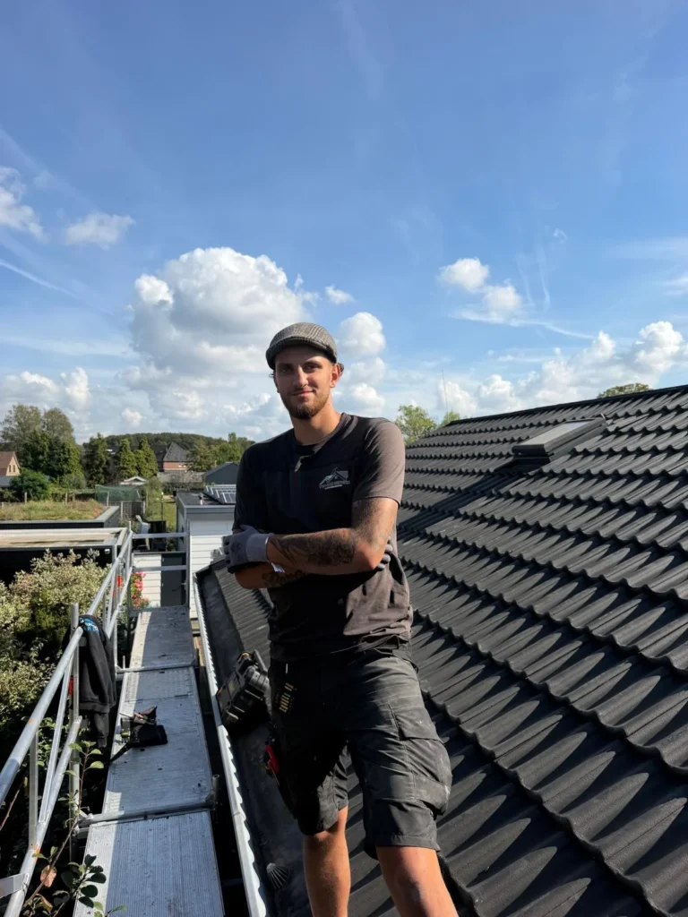 Dakdekker poseert op de steiger naast een nieuw pannendak in Ede